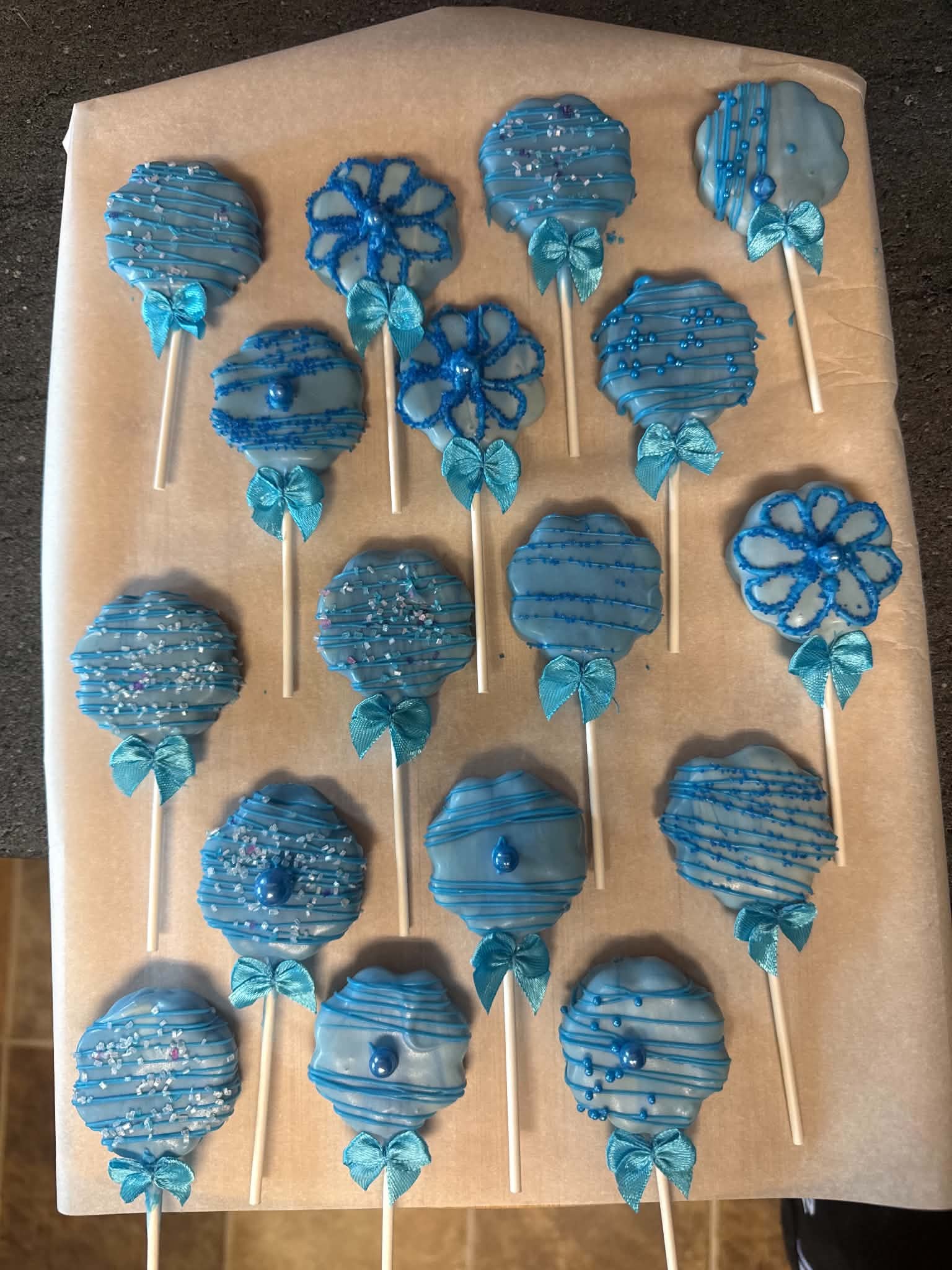 Blue custom cake pops with bows arranged on a tray