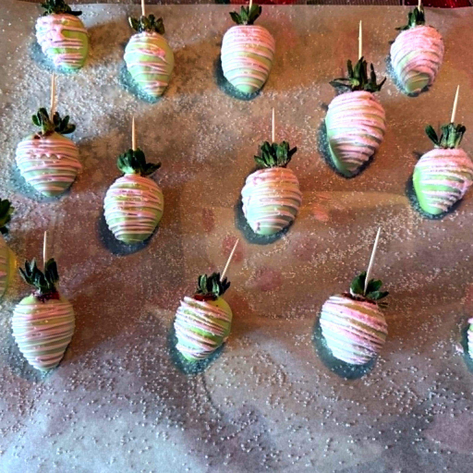 Pink and green chocolate dipped strawberries with decorative drizzle