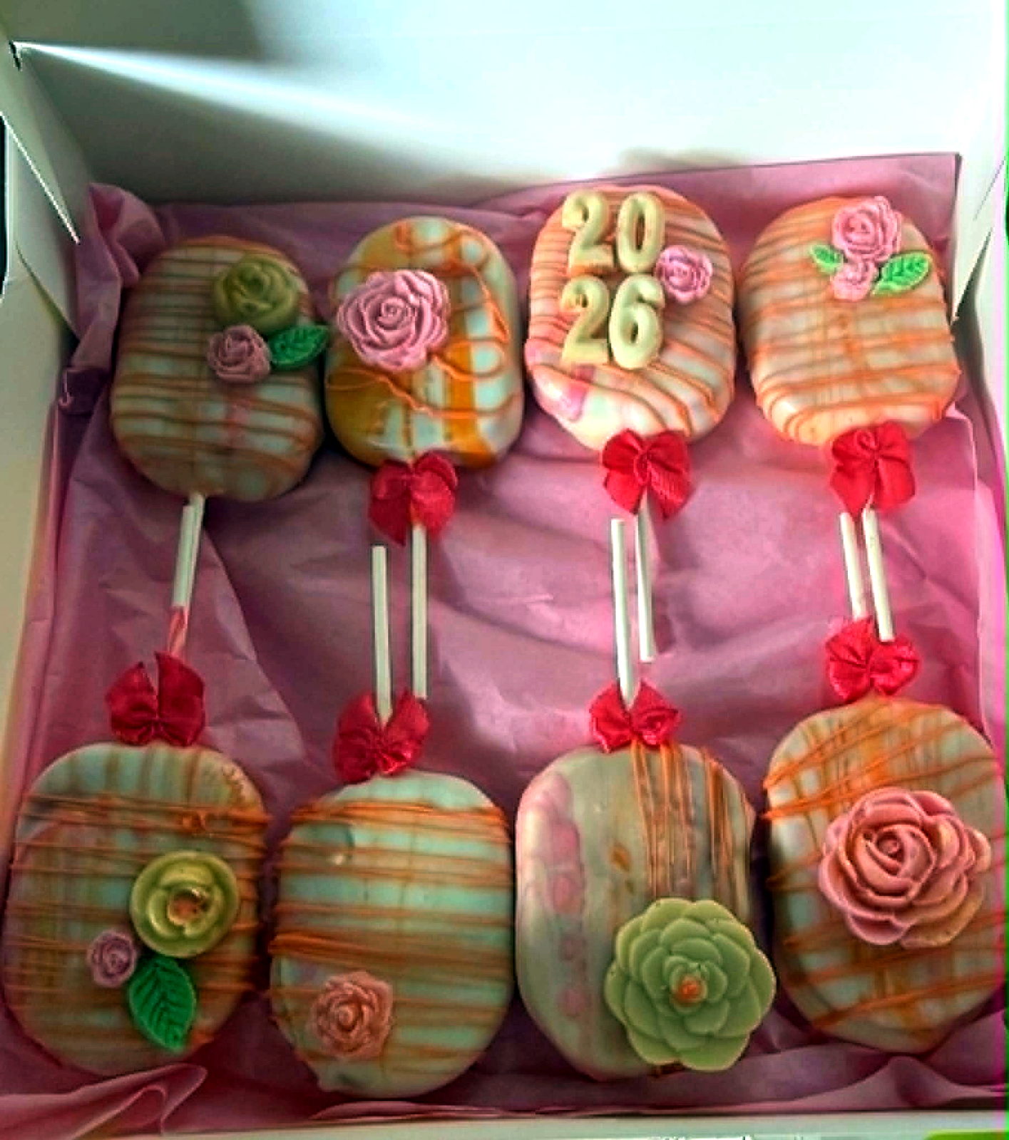 Boxed orange and pink cake pops with a 2026 graduation design