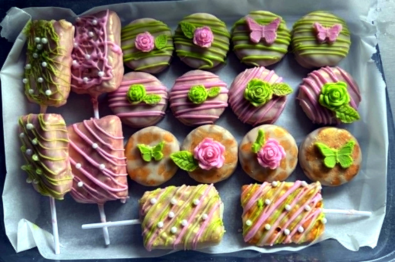 Assorted pink and green dipped pretzels, Oreos, and cake pops in a custom treat box