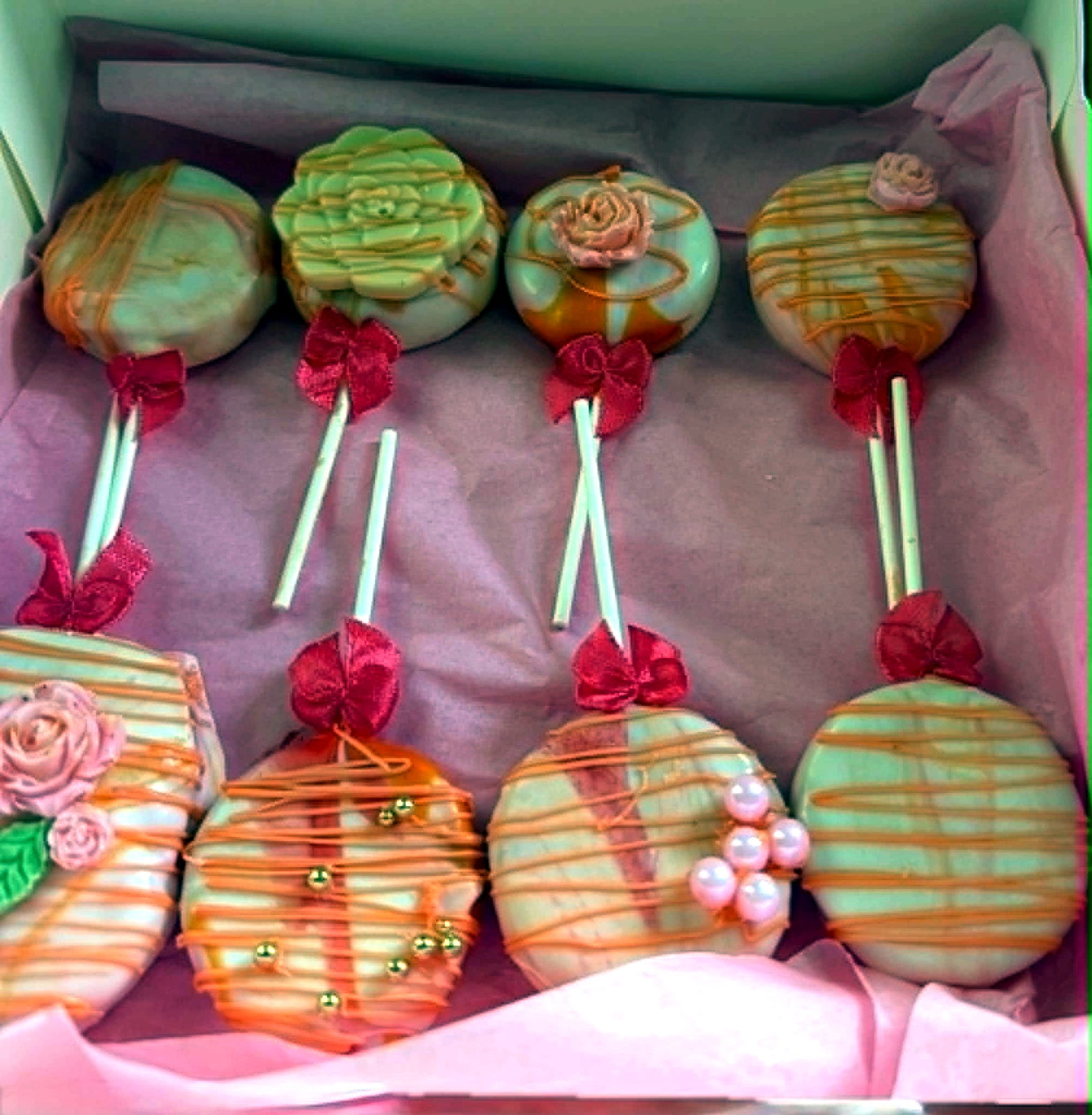 Orange and pink cake pops packed in a gift box with ribbon details