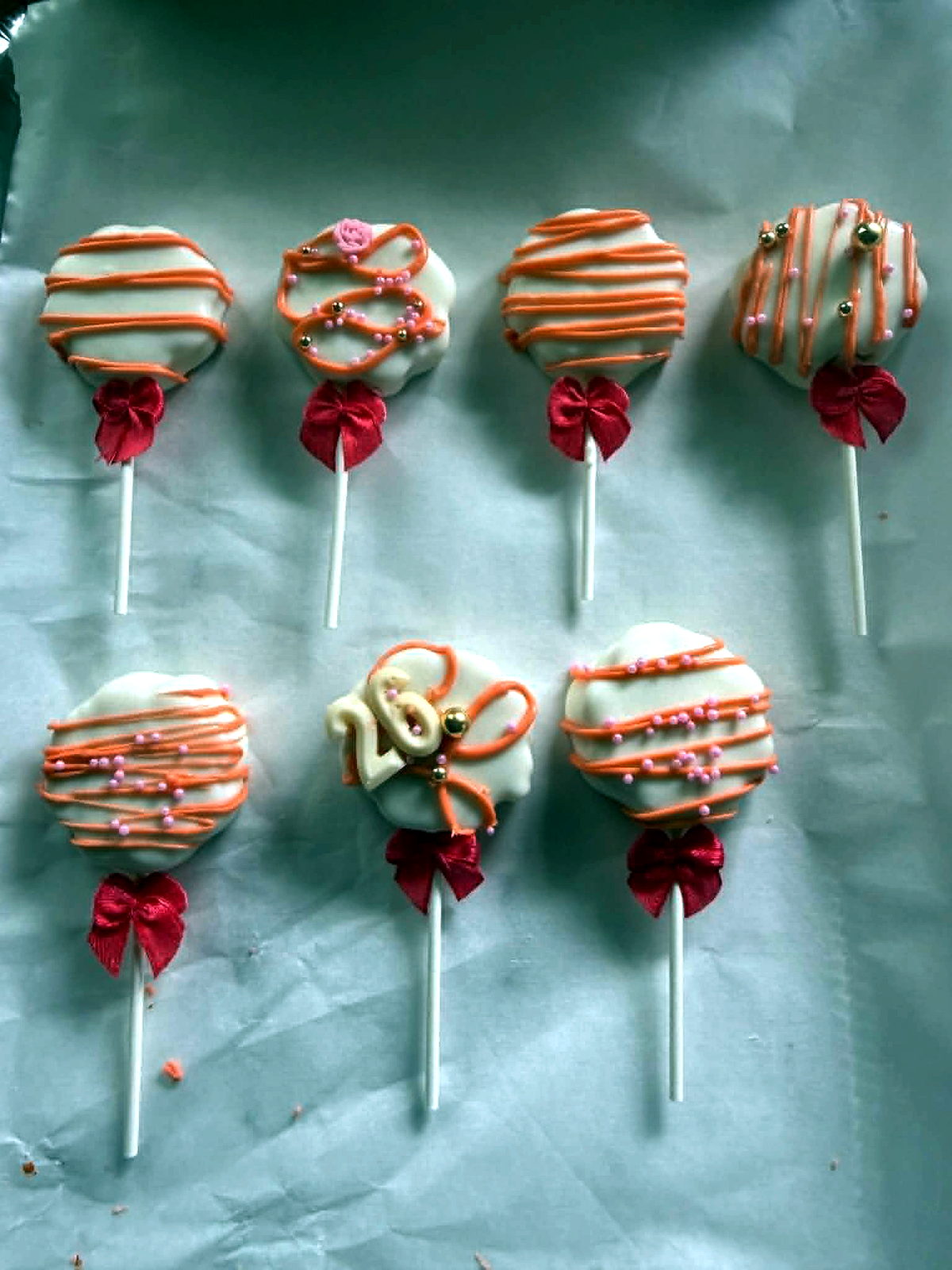 Orange and white decorated cake pops with red bow accents