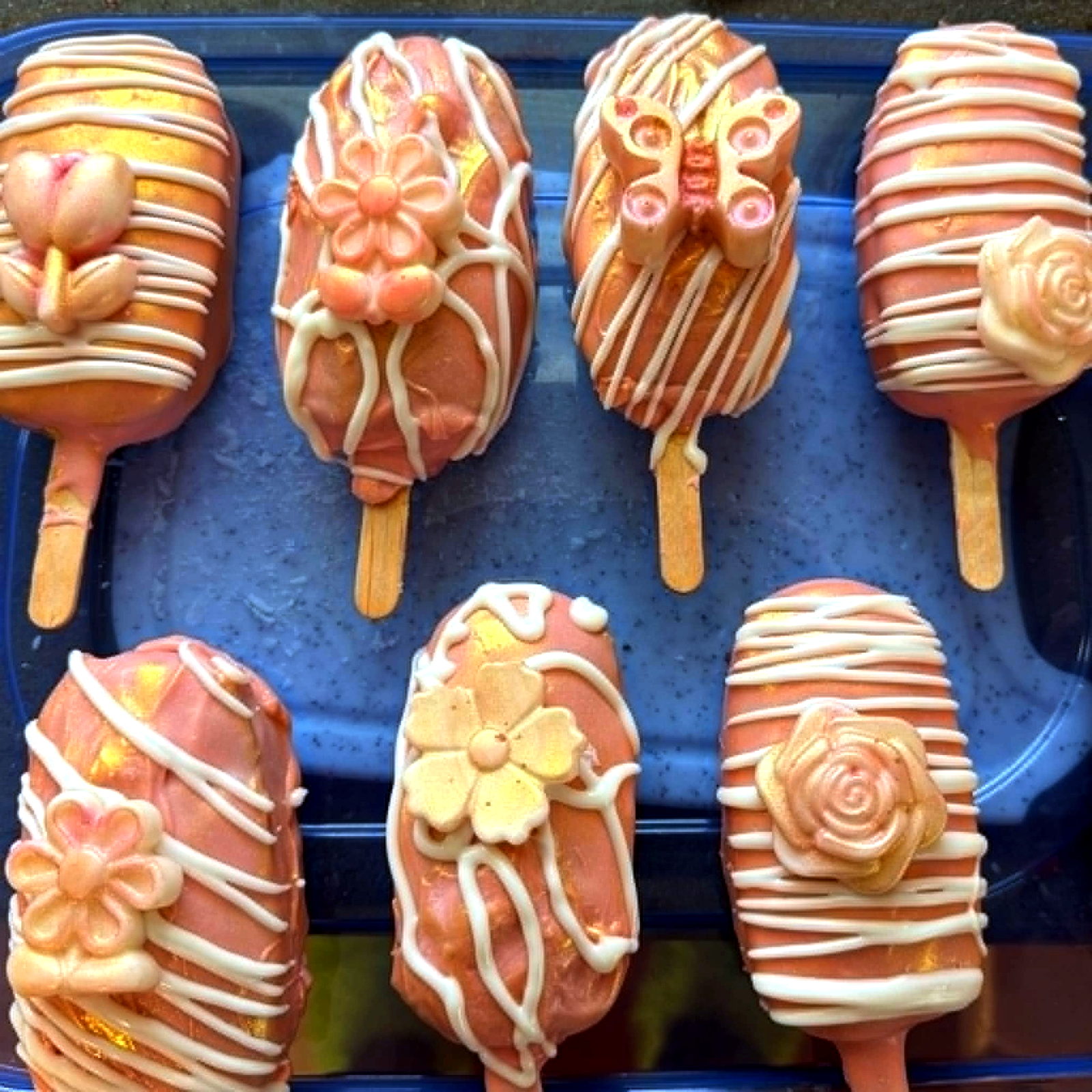 Rose gold cake pops with white drizzle and floral decorations