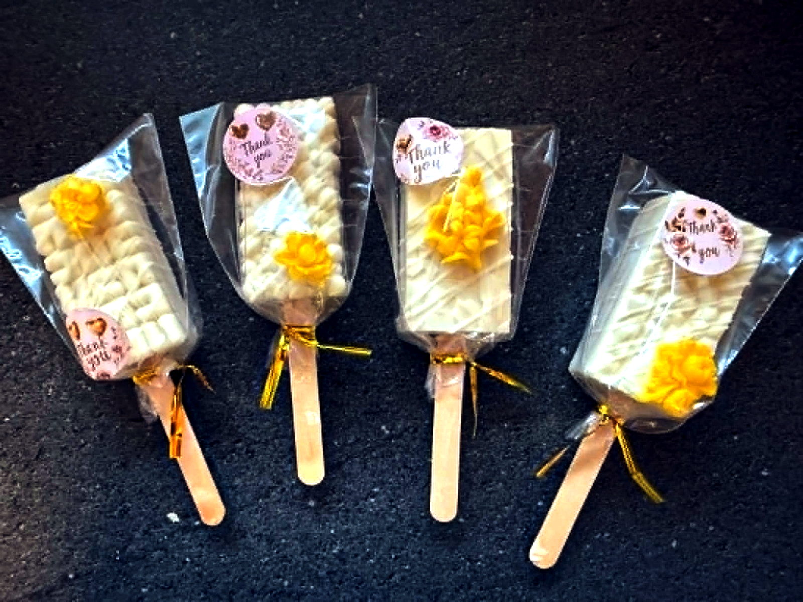Individually wrapped white chocolate treat pops with yellow floral accents